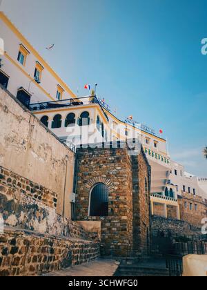 Il distretto di Port Kasbah a Tangeri, Marocco, che unisce finestre ad arco e fondamenta in pietra catturate sotto cieli azzurri il 6 giugno 2024 Foto Stock