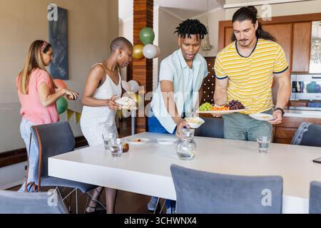 Tavolo con gli amici con cibo e bevande per un incontro informale a casa Foto Stock