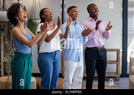 Un gruppo diversificato di professionisti che applaudono e sorridono in un ambiente d'ufficio moderno Foto Stock