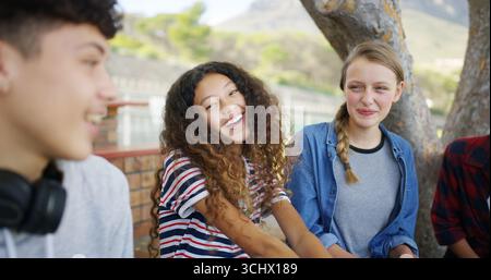 Scuola superiore, felicità e amici all'aperto per parlare, conversare e chiacchierare insieme nel campus. Academy, adolescenti e ragazze che ridono per una storia divertente Foto Stock