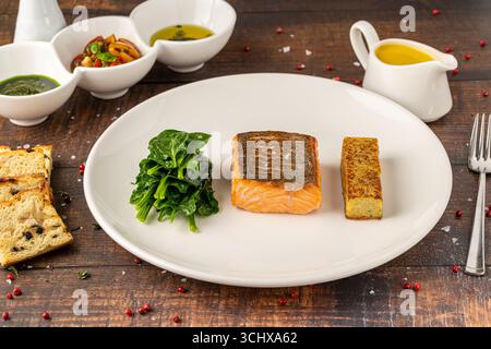 Filetto di salmone scottato servito con spinaci saltati e croquette di patate Foto Stock
