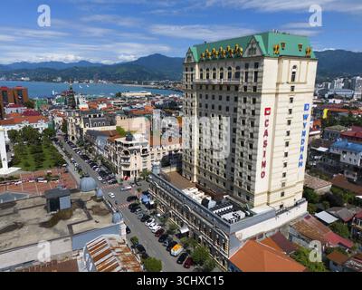 Grande edificio alberghiero in una cittadina costiera con montagne sullo sfondo e vivace scena stradale, vista aerea, Princess Casino, Batumi, Mar Nero, Adja Foto Stock
