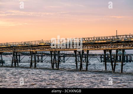 La passerella per il vecchio molo di Birnbeck al tramonto, che si trova nel canale di Bristol a Weston-super-Mare, North Somerset, Regno Unito Foto Stock
