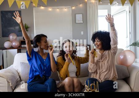 Festeggiate a casa, amici di sesso femminile con fiori e decorazioni, divertendosi insieme Foto Stock