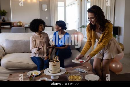 Festeggiamo il compleanno, diverse amiche mangiano torte e parlano nell'accogliente salotto di casa Foto Stock