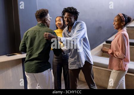 I colleghi afro-americani si salutano calorosamente in un moderno ambiente d'ufficio Foto Stock