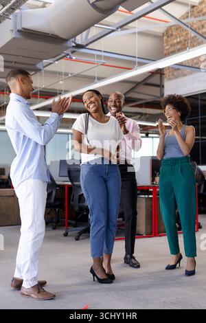 Colleghi che celebrano il successo in un ufficio moderno, sorridono e applaudono insieme Foto Stock