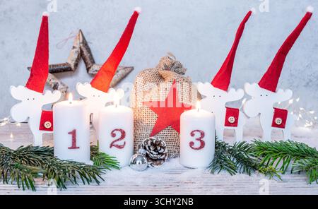 Tre candele accese davanti ai graziosi alci natalizi, il terzo Avvento Foto Stock