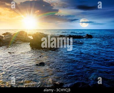costa marina con rocce e massi. concetto di cambiamento di orario diurno e notturno. calmo sfondo delle vacanze estive in riva al mare. una scena meravigliosa per rilassarsi e Foto Stock