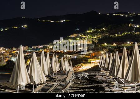 Spiaggia vuota di notte, sedie a sdraio e ombrellone foto notturna della città di Gioiosa marea Foto Stock