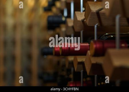 Bottiglie di vino rosso disposte ordinatamente in una griglia di legno, che mostra la bellezza della raccolta e dello stoccaggio dei vini. Foto Stock