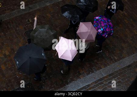 I pedoni camminano sotto la pioggia nel centro di Londra, mentre un avvertimento giallo di temporali è attivo. Foto Stock