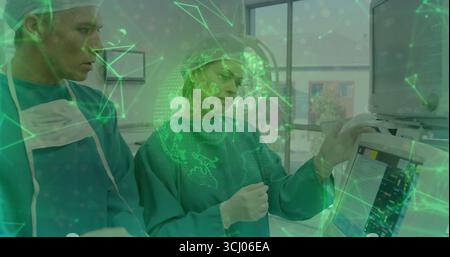 Due chirurghi che monitorano i segni vitali sulla console nella sala operatoria, con cappucci e camici chirurgici Foto Stock