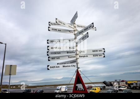 Longyearbyen Airport Signpost con distanze da Global Cities Svalbard Norvegia // SVALBARD, Norvegia — Un cartello all'aeroporto Svalbard Longyearbyen mostra distanze da varie città globali, tra cui Sydpolen (Polo Sud) a 2743 km (1700 miglia), Amburgo a 3326 km (2067 miglia), Parigi a 3326 km (2067 miglia) e Vaasa a 1689 km (1050 miglia). Altre destinazioni indicate sono Oslo, Mosca, Tokyo, Tromsø, Bangkok, Londra e città del Messico. Il cartello indica anche il Polo Nord. L'aeroporto Svalbard di Longyearbyen è l'aeroporto più settentrionale del mondo con voli commerciali di linea. Il Foto Stock