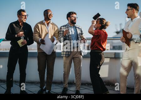Team di lavoro diversificato che festeggiano sul tetto al tramonto Foto Stock