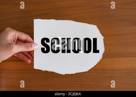 Scuola. La mano della donna tiene un pezzo di carta con un biglietto, vintage. Istruzione, apprendimento, successo, conoscenza, disciplina. Note B1983 scuola Foto Stock
