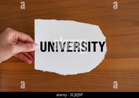 Università. La mano della donna tiene un pezzo di carta con un biglietto, vintage. Accademia, studio, successo, conoscenza, istruzione. Note B1983 University Foto Stock