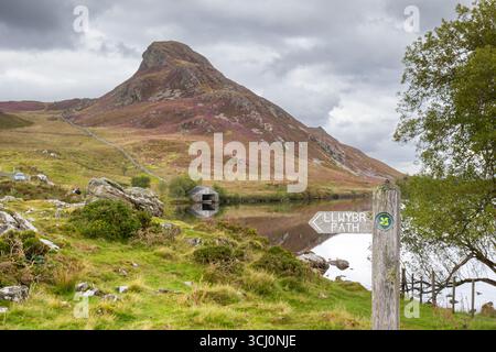 Galles del Nord, Regno Unito. Settembre 2025. Meteo nel Regno Unito: Cartello del National Trust per IL SENTIERO, LLWYBR di fronte ai laghi Cregennan (Llynau Cregennan) nel Galles del Nord, guardando in alto verso la cima della collina di Pared y Cefn-Hir, sotto un cielo buio e tempestoso. Credito Lee Hudson/Alamy Foto Stock