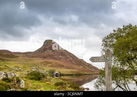 Galles del Nord, Regno Unito. Settembre 2025. Meteo nel Regno Unito: Cartello del National Trust per IL SENTIERO, LLWYBR di fronte ai laghi Cregennan (Llynau Cregennan) nel Galles del Nord, guardando in alto verso la cima della collina di Pared y Cefn-Hir, sotto un cielo buio e tempestoso. Credito Lee Hudson/Alamy Foto Stock