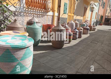 Tradizionali cesti africani intrecciati sulla strada del centro storico in Italia. Affari privati, mercato e vendite. Oggetti per la cucina, la casa, fatti a mano. Foto Stock