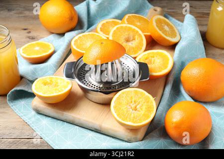 Succo d'arancia appena spremuto, frutta, centrifuga e asciugamano sul tavolo di legno Foto Stock