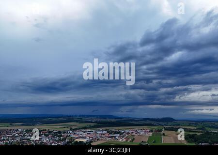 4 settembre 2025, Baden-Württemberg, Böhmenkirch: Le nuvole di tempesta scura si stanno radunando dietro Böhmenkirch nell'alb svevo. Il servizio meteorologico tedesco avverte di temporali estremi e grandine nel sud della Germania. (Foto scattata con un drone) foto: Marius Bulling/onw-images/dpa Foto Stock
