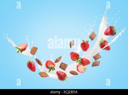 Spruzzare il latte con cialde di mais dolce e fragole fresche in aria su sfondo azzurro. Colazione salutare Foto Stock