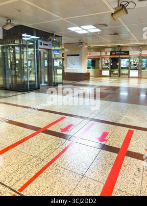 Interno vuoto di una moderna stazione della metropolitana con frecce rosse direzionali sul pavimento e un ascensore di vetro vicino alla MRT Raffles Place Singapore Foto Stock
