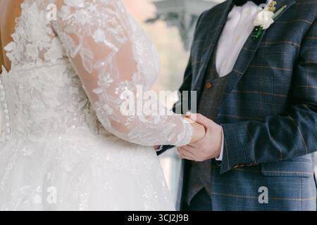 La coppia scambia i voti tenendo per mano in un romantico ambiente all'aperto circondato da fiori al tramonto. Foto Stock
