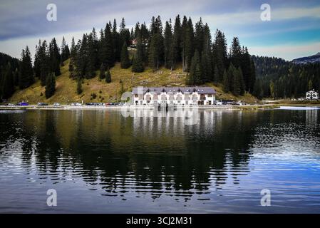Una vista panoramica di un grande e tradizionale rifugio di montagna, probabilmente un albergo, situato sulle rive del Lago di Misurina nelle Dolomiti. L'edificio è backe Foto Stock