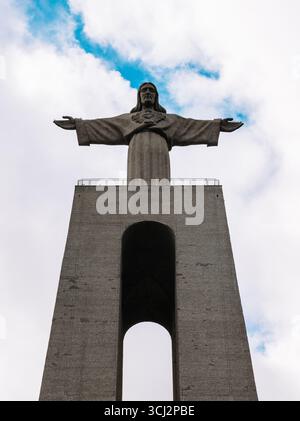Una foto dall'angolo basso del santuario di Cristo Rei, un famoso monumento di Almada, vicino a Lisbona. La fotografia mette in evidenza la colossale statua di Cristo Foto Stock
