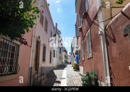 Una vista a livello della strada di un affascinante e stretto vicolo in una città storica, caratterizzata da edifici classici e tradizionali marciapiedi di ciottoli. La fotografia h Foto Stock