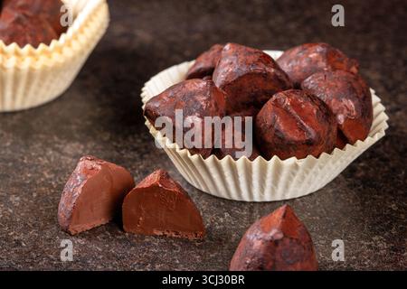 Una vista ravvicinata delle decadenti caramelle al tartufo splendidamente disposte in un affascinante cestino di carta, che mostra le loro ricche texture e la loro presentazione elegante, Foto Stock