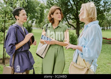Tre donne di mezza età che conversano all'aperto in un ambiente di Green Park Foto Stock