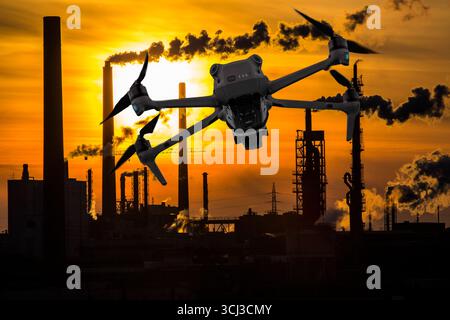 Symbolbild, Fotomontage, Aufklärung, Spionage mit Drohnen in Industrieanlagen, kritischer Infrastruktur, Drohne fliegt auf einen Industriekomplex zu, Chemiewerk, Ausspähen durch Kameradrohnen, Drohnen Spionage *** immagine simbolica, fotomontaggio, ricognizione, spionaggio con droni in impianti industriali Foto Stock
