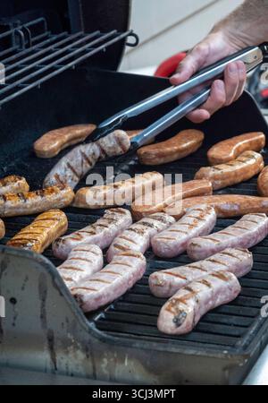 Salsicce bratwurst e italiane grigliate su una piastra Blackstone presso un barbecue sul cortile, 2025, Great Falls, MT, USA Foto Stock