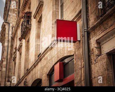 Il segno quadrato rosso vuoto è appeso a un negozio di pietra calcarea su una stretta strada francese, offrendo spazio per le copie per il branding contro la pietra intemprata e la pietra lavorata Foto Stock