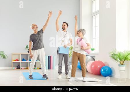 Attiva allegra attraente vestibilità anziana donna anziana, uomo allenatore 5 in alto allenarsi in club sportivo Foto Stock