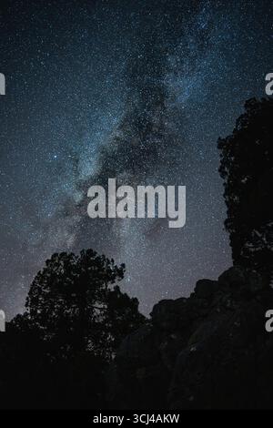 Cielo stellato notturno con la via Lattea sopra la silhouette rocciosa Foto Stock