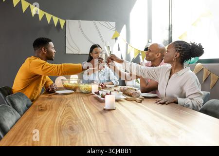 Festeggiate insieme, amici che brinano bicchieri di champagne a cena, condividendo gioia Foto Stock