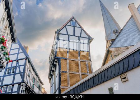 Hattingen, Germania - 14 giugno 2025: Case intramontabili in legno e una guglia della chiesa sotto un cielo drammatico a Hattingen, Germania. Foto Stock