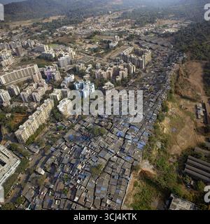 Veduta aerea dei tetti densi e blu scuro di uno slum che si accostano ai moderni e alti edifici, mostrando un netto contrasto, Mumbai, Maharashtra, India. Foto Stock