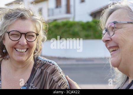 Due donne anziane allegre si divertono a vicenda all'aperto, condividendo risate e felicità Foto Stock
