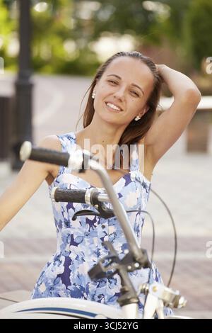 Una giovane ciclista seduta a guardare la macchina fotografica sorridente Foto Stock