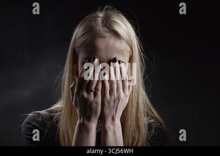 Donna piangente che copre il viso con le mani Foto Stock