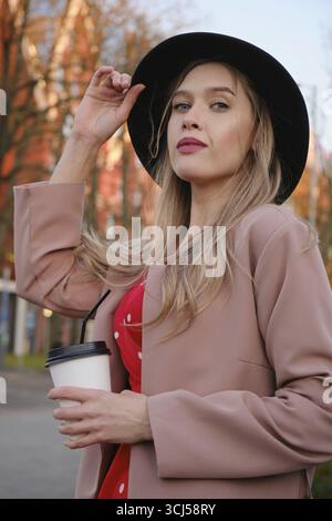 Giovane donna di lusso che posa in città con una tazza da caffè Foto Stock