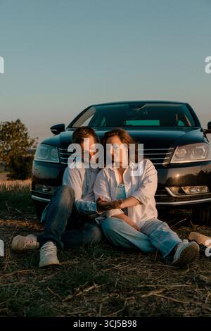 Coppia seduta insieme davanti alla macchina Foto Stock