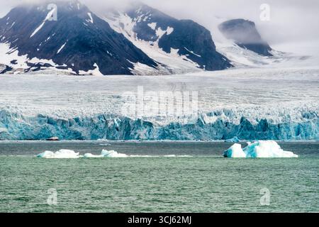 Ghiacciaio Lilliehöökfjorden Spitsbergen Svalbard Norvegia // LILLIEHÖÖKFJORDEN, Svalbard — gli Iceberg distaccati dal ghiacciaio Lilliehöökfjorden galleggiano nelle acque artiche al largo della costa di Spitsbergen, nelle Svalbard, Norvegia. Il Lilliehöökfjorden è un ghiacciaio situato nella parte nord-occidentale di Spitsbergen, la più grande isola dell'arcipelago delle Svalbard. Le Svalbard sono un arcipelago situato nell'Oceano Artico, a circa metà strada tra la Norvegia continentale e il Polo Nord. La regione è conosciuta per i suoi spettacolari paesaggi glaciali e l'abbondante fauna selvatica. Foto Stock