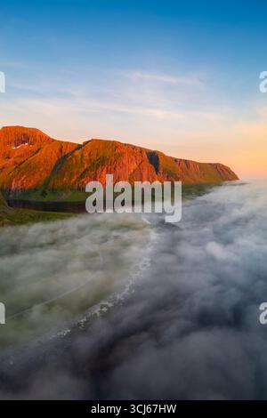 Vista aerea delle nuvole basse che si muovono nella città di Eggum al sole di mezzanotte in estate. Eggum Unstad, Vestvagoy Lofoten, Isole, Norvegia, Europa. Foto Stock