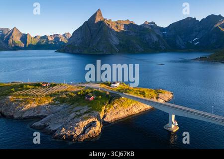 Vista aerea del monte Olstinden e dell'isola di Sakrisøya nella baia di Reine durante l'alba al sole di mezzanotte in estate. Isole Lofoten, Norvegia. Foto Stock